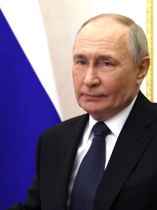 Der russische Präsident Wladimir Putin sitzt an einem Schreibtisch vor einer Russland-Flagge