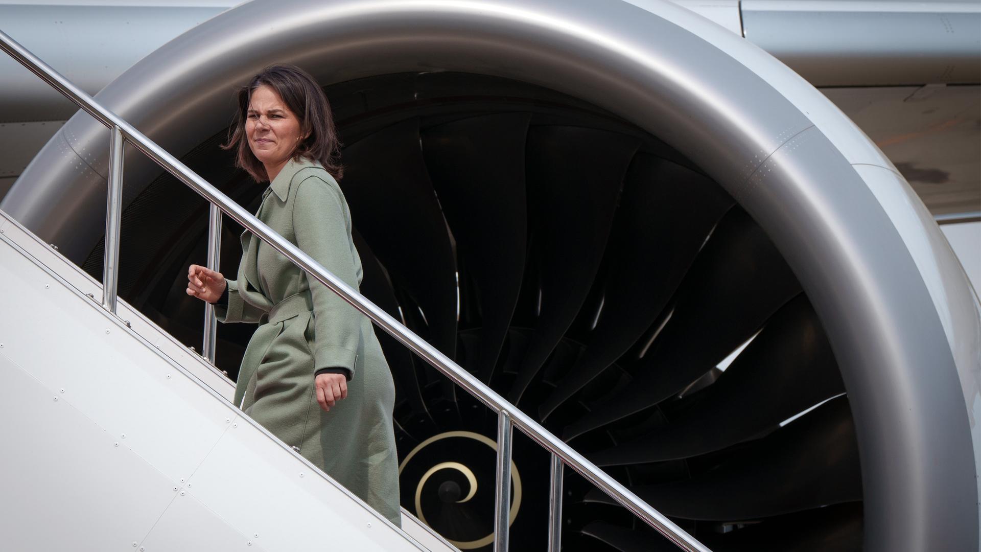 Bundesaußenministerin Baerbock (Bündnis 90/Die Grünen) auf einer Flugzeugtreppe; im Hintergrund ist ein Triebwerk eines Airbus A350 der Luftwaffe zu sehen.