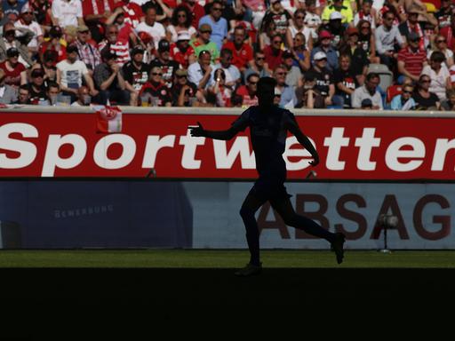 Die Aufschrift "Sportwetten" steht auf einer Werbebande bei einem Fußballspiel.