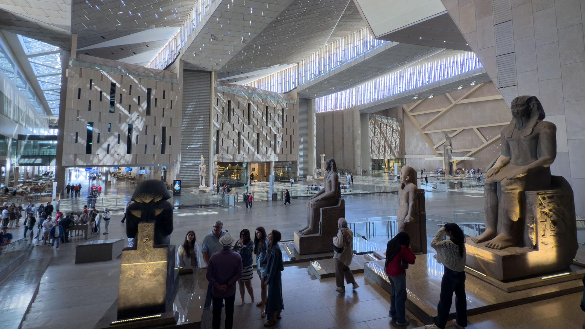 Besucher betrachten Exponate in einer Halle des Großen Ägyptischen Museums Besucher betrachten Exponate in einer Halle des Großen Ägyptischen Museums