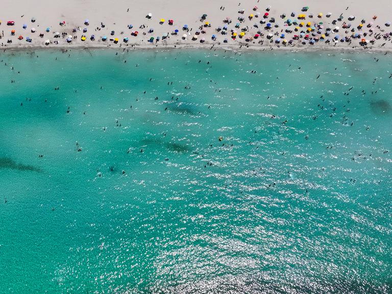 Ein Strandabschnitt mit Menschen und das Meer im türkischen Izmir sind aus der Drohnenperspektive zu sehen