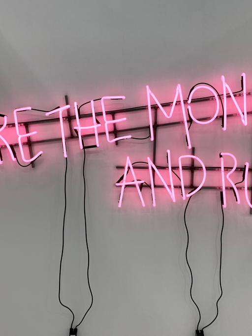 Das Werk „Ne travallez jemais“ (2022) von Kerim Seiler am Stand der Galerie Sexauer auf der Art Cologne. In rosa Buchstaben steht in mit Leuchtstoffröhren vor weisser Wand geschrieben "Take the money and run".