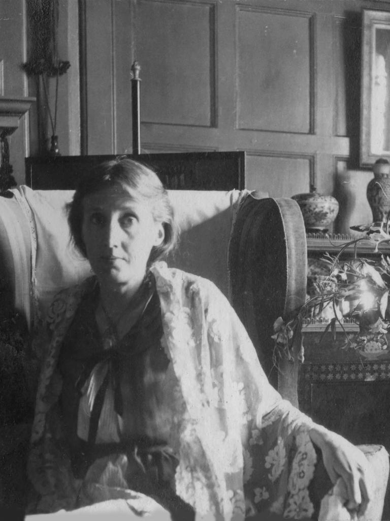 Virginia Woolf sitzt in einem Sessel neben einem Blumenstrauß.