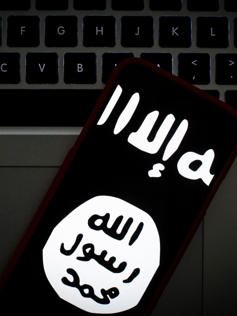 Das Logo des islamischen Staates auf dem Bildschirm eines Smartphones. Im Hintergrund ein Laptop.