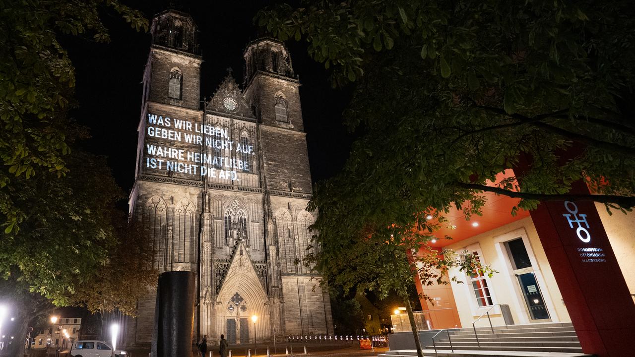 Auf den Magdeburger Dom ist in der Dunkelheit der Spruch projiziert: "Was wir lieben, geben wir nicht auf. Wahre Heimatliebe ist nicht die AfD." 