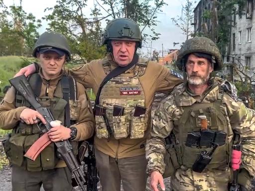 Der Gründer der Wagner Söldnertruppe Jewgeni Prigoschin steht mit zwei seiner Soldaten vor einem zerstörten Straßenzug in der ukrainischen Stadt Bachmut.