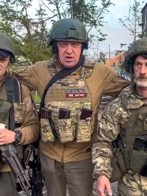 Der Gründer der Wagner Söldnertruppe Jewgeni Prigoschin steht mit zwei seiner Soldaten vor einem zerstörten Straßenzug in der ukrainischen Stadt Bachmut.