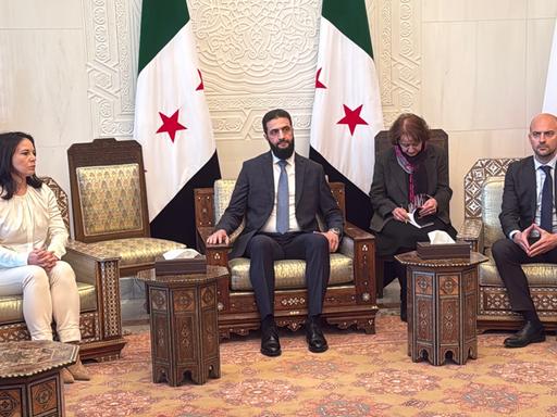 Bundesaußenministerin Baerbock (links), ihr französischer Amtskollege Barrot (rechts) und der neue syrische Machthaber al-Scharaa (Mitte) sitzen nebeneinander auf Sesseln.