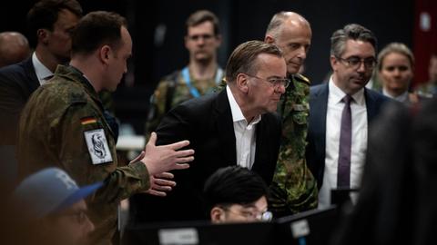 Bundesverteidigungsminister Boris Pistorius im Gespräch mit Soldaten und Zivilisten; er schaut konzentriert auf einen Bildschirm.