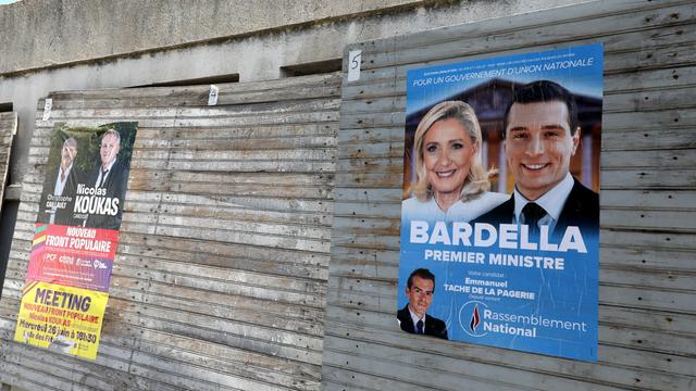 Zwei Wahlplakate mit französischen Politikern hängen an einem Bretterzaun.