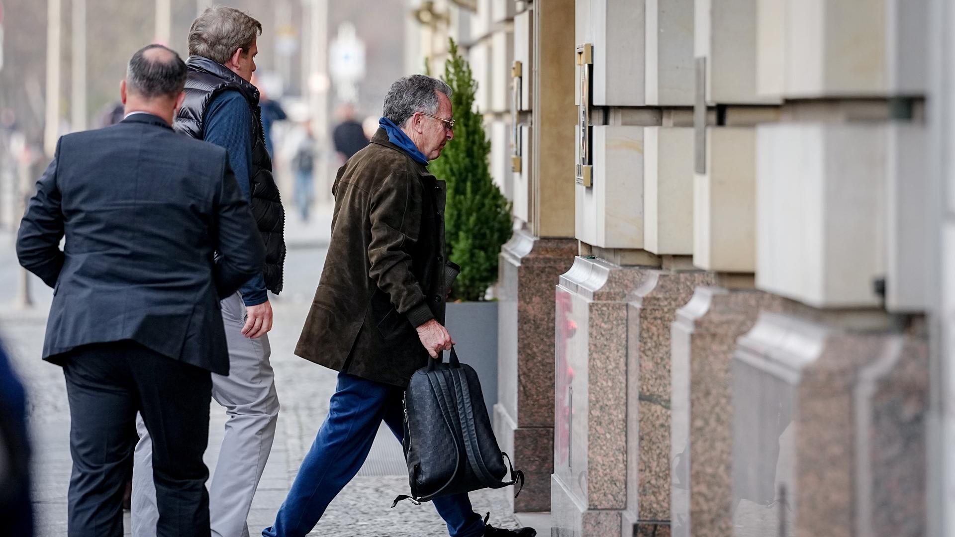 Man sieht Witkoff von der Seite, wie er auf einem Bürgersteig in den Hoteleingang geht. Er trägt eine Tasche. Hinter ihm zwei weitere Personen.