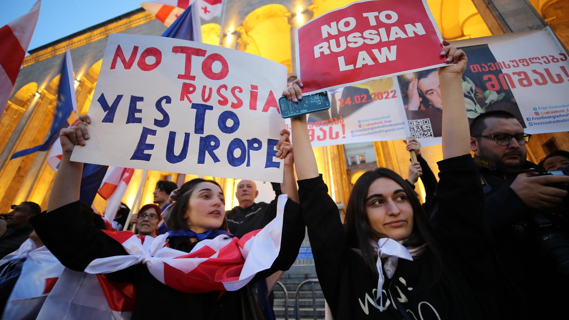 In Georgien halten zwei Teilnehmerinnen einer Demonstration Plakate in die Höhe. Auf einem steht "No to Russia, Yes to Europe", auf dem anderen steht "No to Russian Law".  