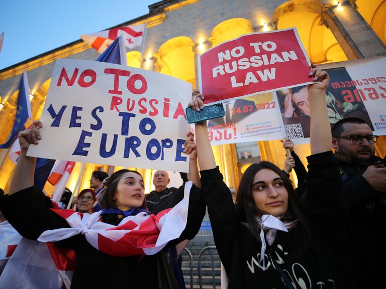 In Georgien halten zwei Teilnehmerinnen einer Demonstration Plakate in die Höhe. Auf einem steht "No to Russia, Yes to Europe", auf dem anderen steht "No to Russian Law".  