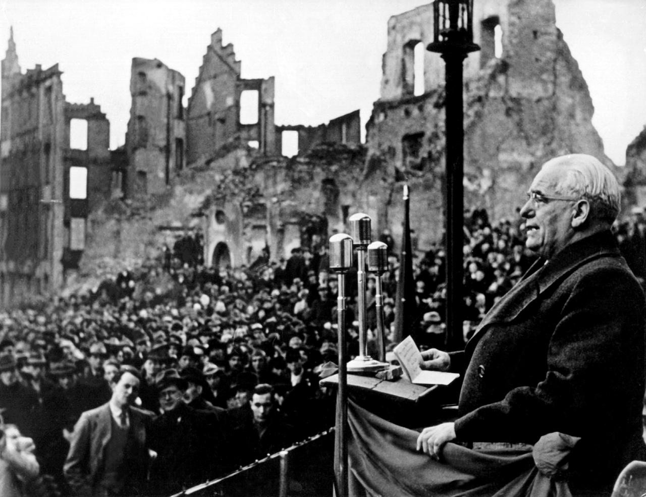 Historisches Schwarz-Weiß-Foto von Wilhelm Pieck, der vor den Ruinen Frankfurt am Mains eine Rede hält.