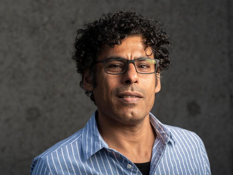 Porträt von Usama Al Shahmani mit offenem, etwas skeptischem Blick