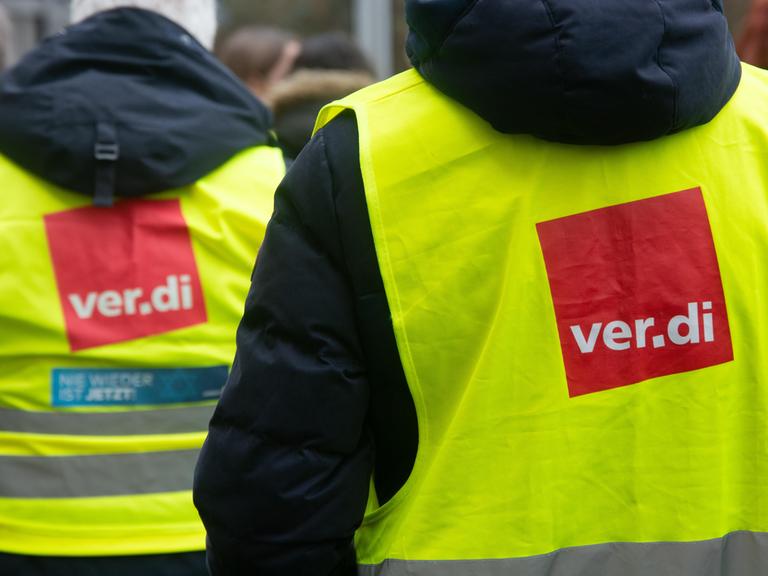 Streik des öffentlichen Dienst: Menschen mit Warnwesten stehen beieinander. Auf den gelben Westen ist das Logo der Gewerkschaft Verdi: ein rotes Viereck mit weißer Schrift "Verdi".