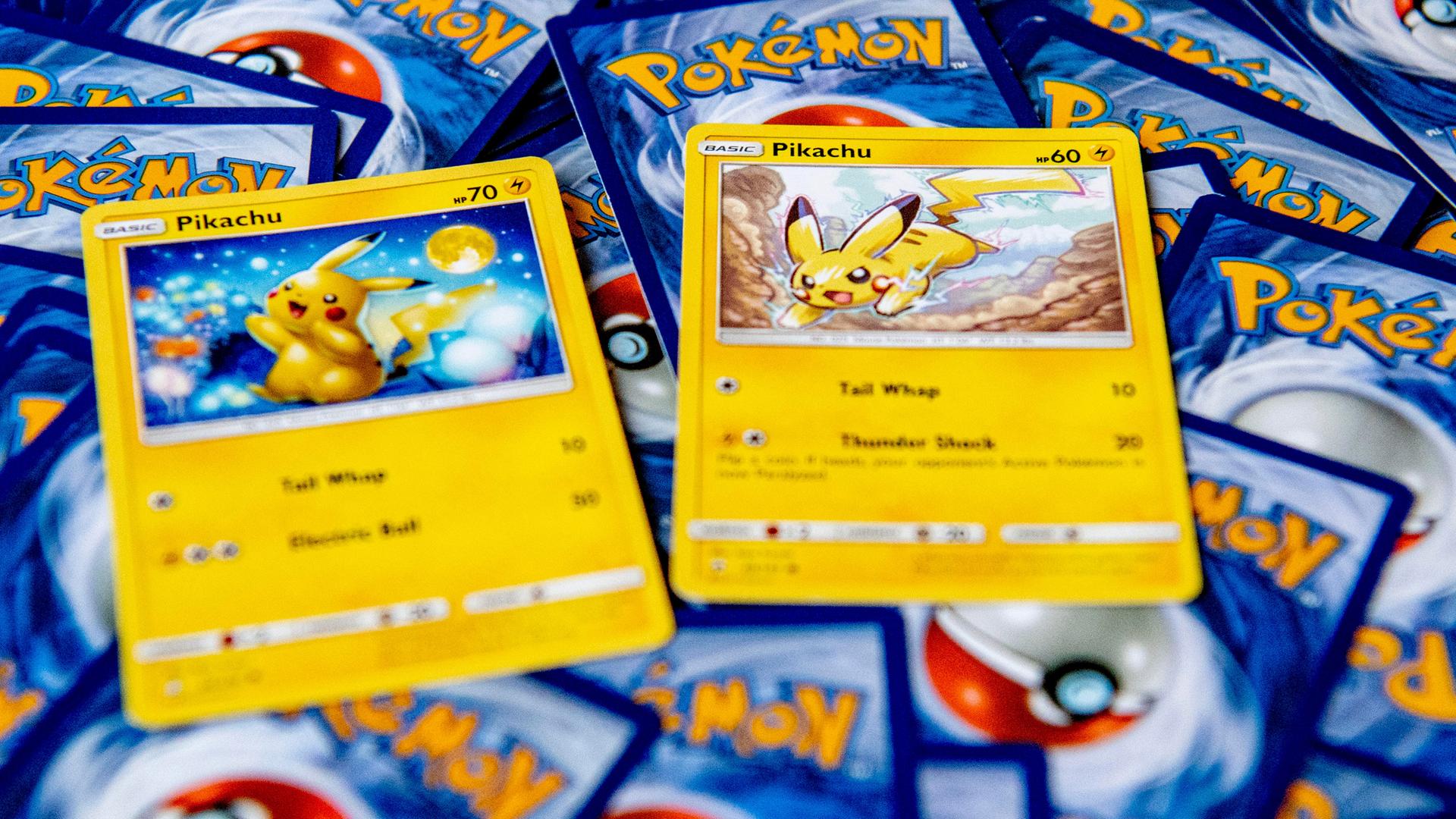 Zwei Pokémon-Karten von Pikachu liegen auf einem Haufen weiterer Pokémon-Karten, von denen man nur die Rückseite sieht.