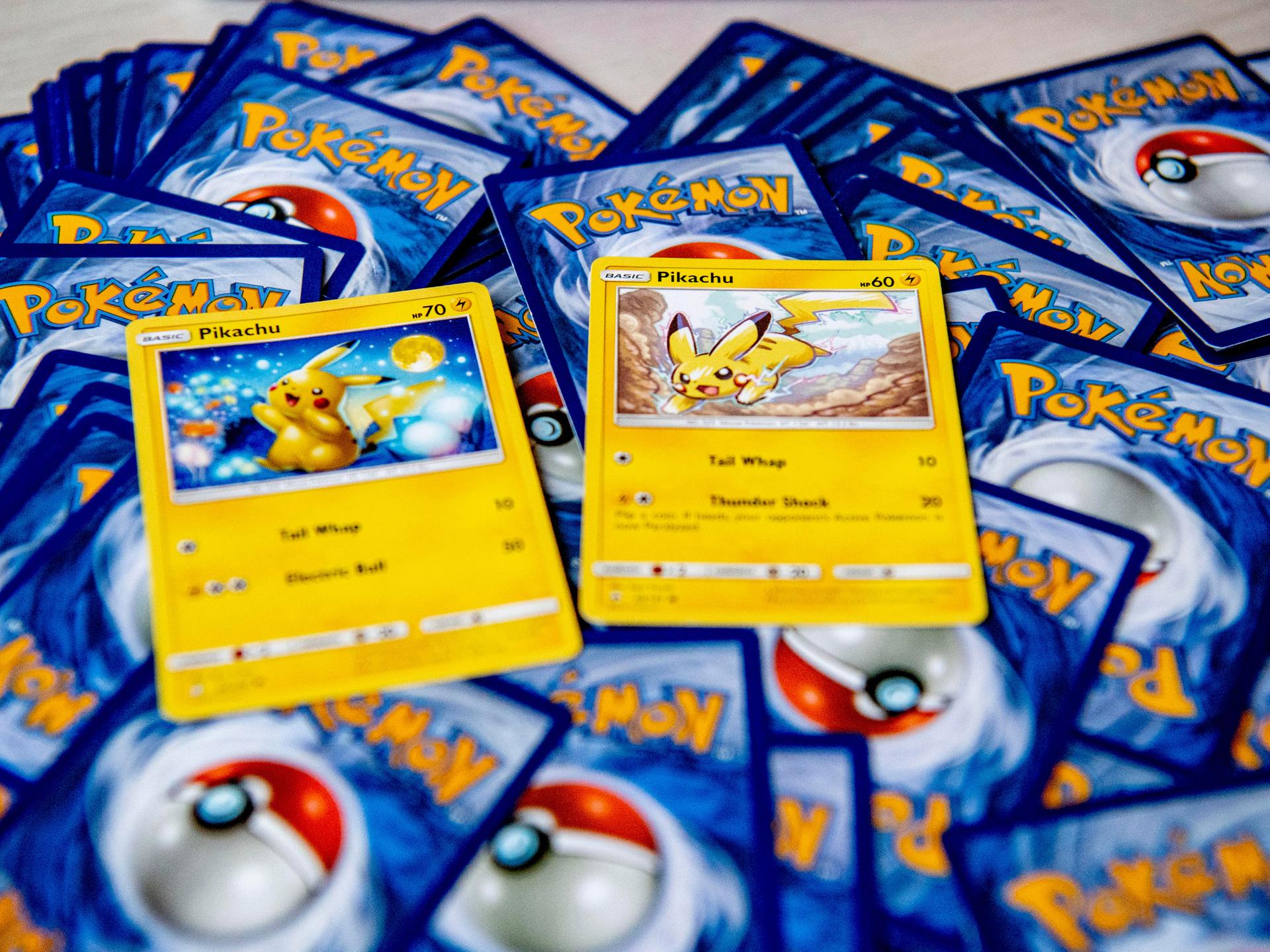 Zwei Pokémon-Karten von Pikachu liegen auf einem Haufen weiterer Pokémon-Karten, von denen man nur die Rückseite sieht.