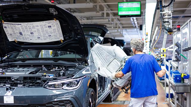 Ein Mitarbeiter montiert in einem Fahrzeug im VW Werk einen Autositz.