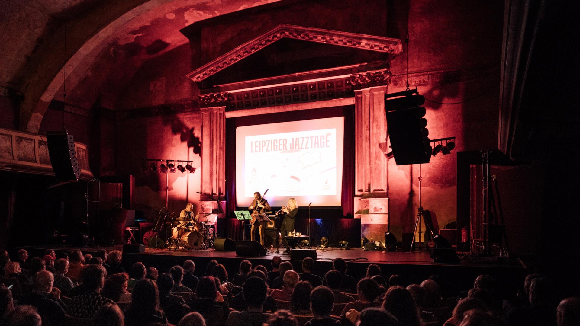 Blick auf die Bühne der Musikalischen Komödie Leipzig, auf der ein Konzert der Leipziger Jazztage stattfindet, das mit einem großen Aufhänger auf der Bühne kenntlich gemacht ist.