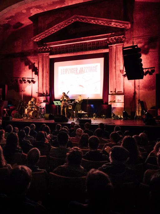 Blick auf die Bühne von UT Connewitz, auf der ein Konzert der Leipziger Jazztage stattfindet, das mit einem großen Aufhänger auf der Bühne kenntlich gemacht ist.