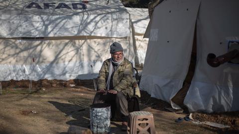 Türkei, Kahramanmaras: Ein Mann sitzt vor seinem Zelt und wärmt sich in einem Behelfslager für Menschen, die ihre Häuser im Epizentrum des Erdbebens verloren haben.