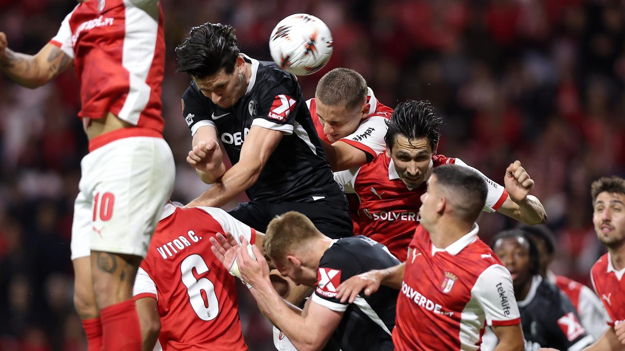 Mehrere Fußball-Spieler versuchen den Ball mit dem Kopf zu erreichen.