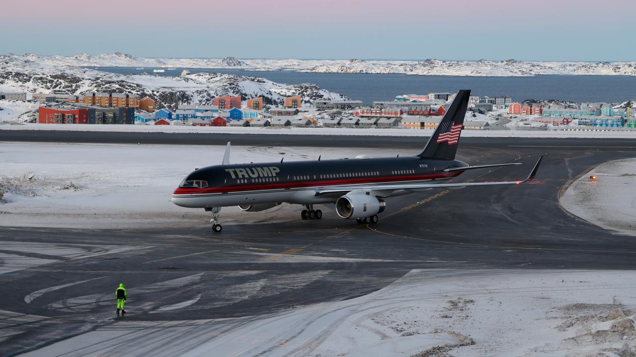 Ein Flugzeug mit dem Schriftzug "Trump" darauf steht auf einer Landebahn, auf der Schnee liegt. Dahinter ist eine Ansammlung von Häusern zu sehen.