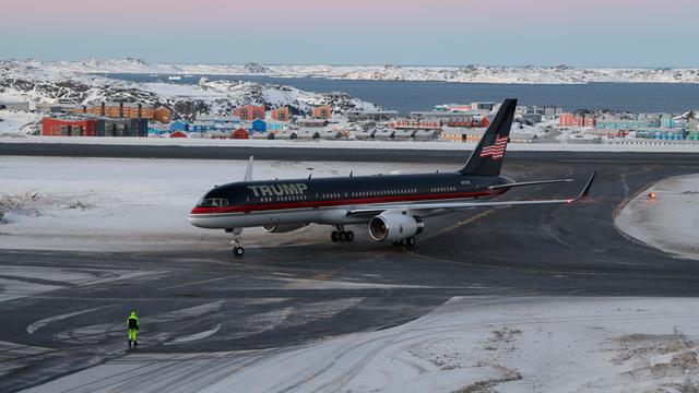 Ein Flugzeug mit dem Schriftzug "Trump" darauf steht auf einer Landebahn, auf der Schnee liegt. Dahinter ist eine Ansammlung von Häusern zu sehen.