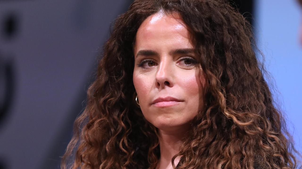 Porträt der Journalistin Alena Jabarine. Sie guckt ganz leicht an der Kamera vorbei. Hinter den gelockten Haaren ist der Hintergrund in blautönen zu erkennen.