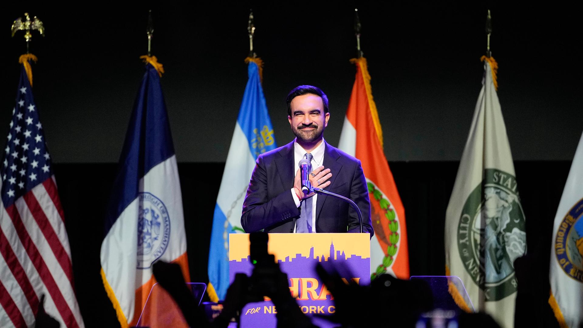 Zohran Mamdani spricht nach seinem Sieg bei den Bürgermeisterwahlen. Hinter ihm sind verschiedene Flaggen.
