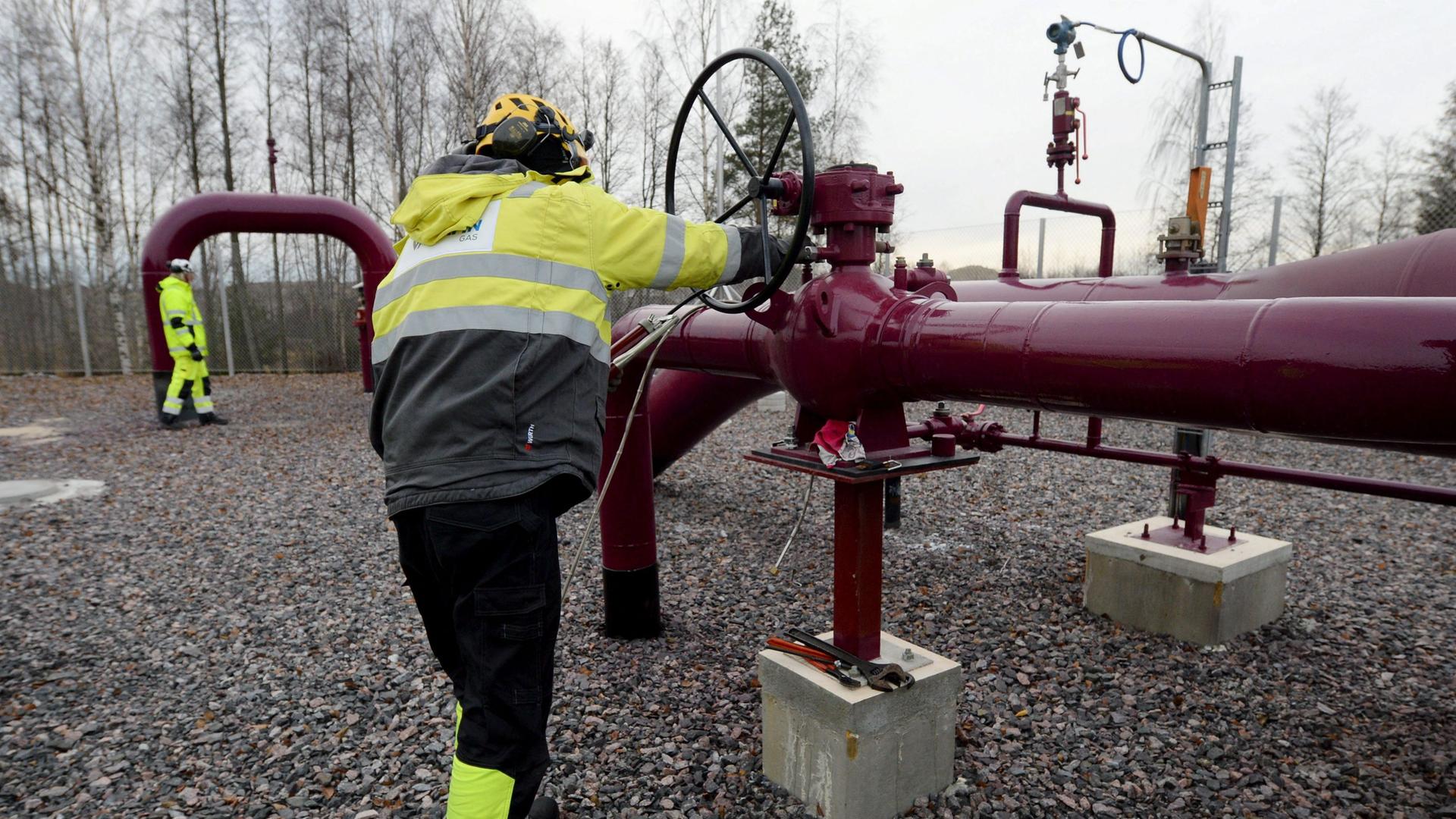 Ein Mitarbeiter dreht ein Öffnungsventil an einer roten Gas-Pipeline.
