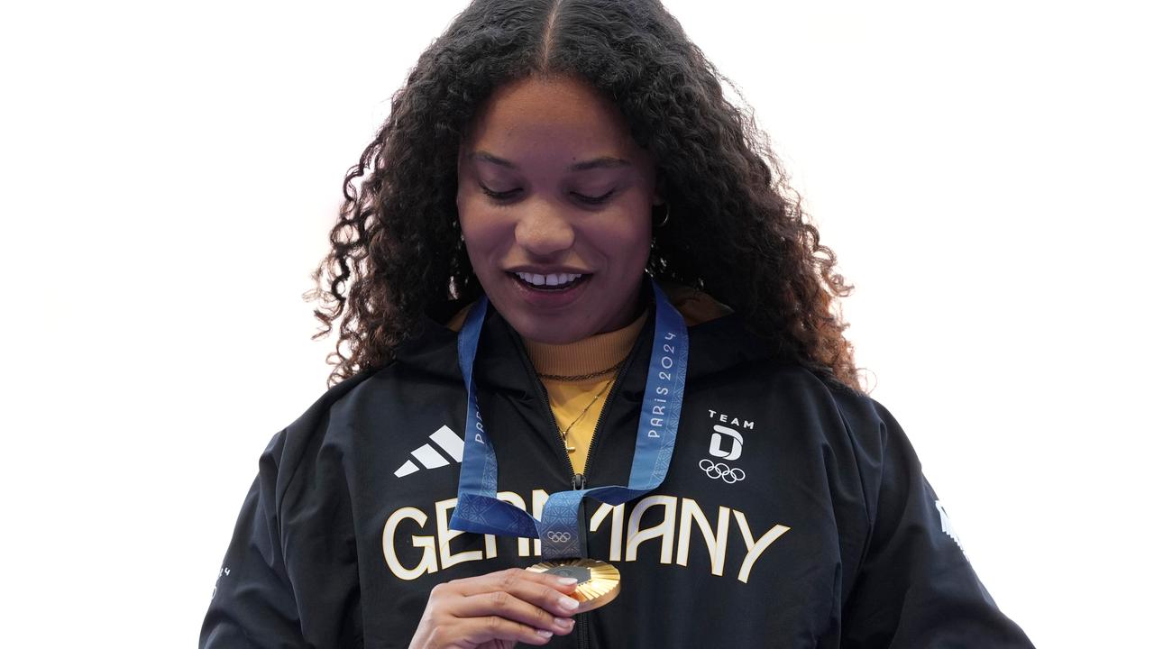 Ogunleye steht auf dem Podium und sieht sich ihre Goldmedaille an.