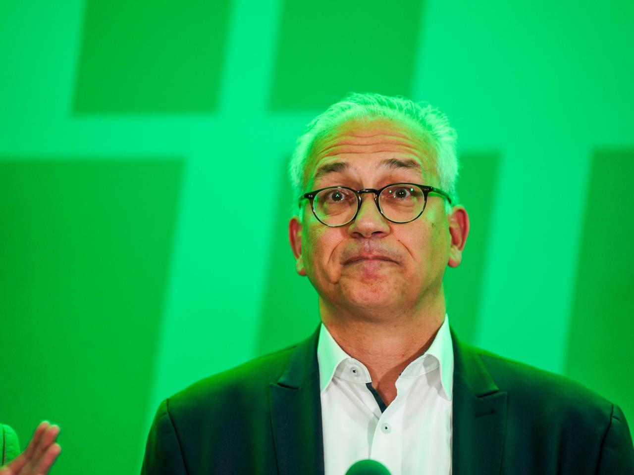Tarek Al-Wazir (Bündnis 90 / Die Grünen), stellvertretender Ministerpräsident und Wirtschaftsminister von Hessen, steht in grünes Licht getaucht vor seinen Parteifreunden.