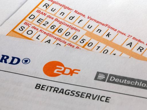  Nahaufnahme von einem Briefbogen mit ARD- und ZDF-Logo und einem Überweisungsträger.