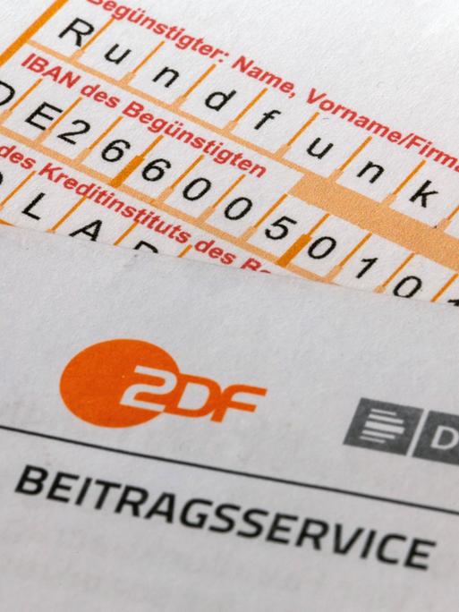  Nahaufnahme von einem Briefbogen mit ARD- und ZDF-Logo und einem Überweisungsträger.