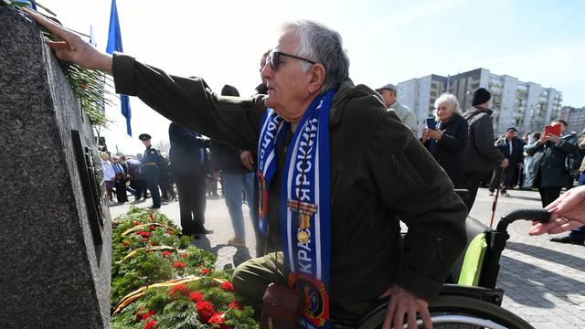 Ein Mann legt Blumen an einem Denkmal nieder.