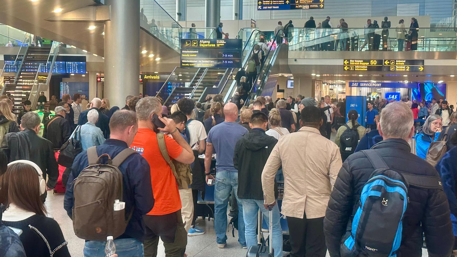 Viele Menschen stehen in einer Halle am Flug-Hafen in der Stadt Kopenhagen. 