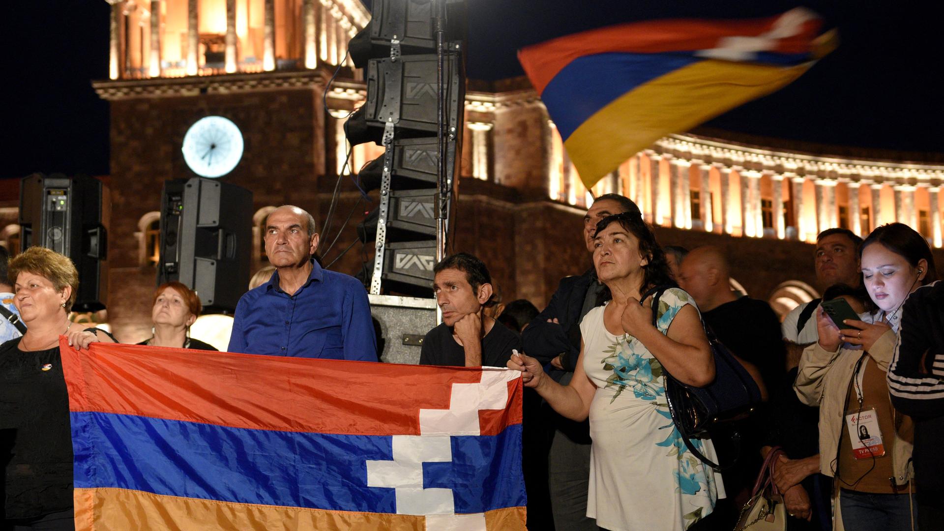 Menschen halten bei einer Anti-Regierungs-Kundgebung im Stadtzentrum von Eriwan eine Fahne von Berg-Karabach. 