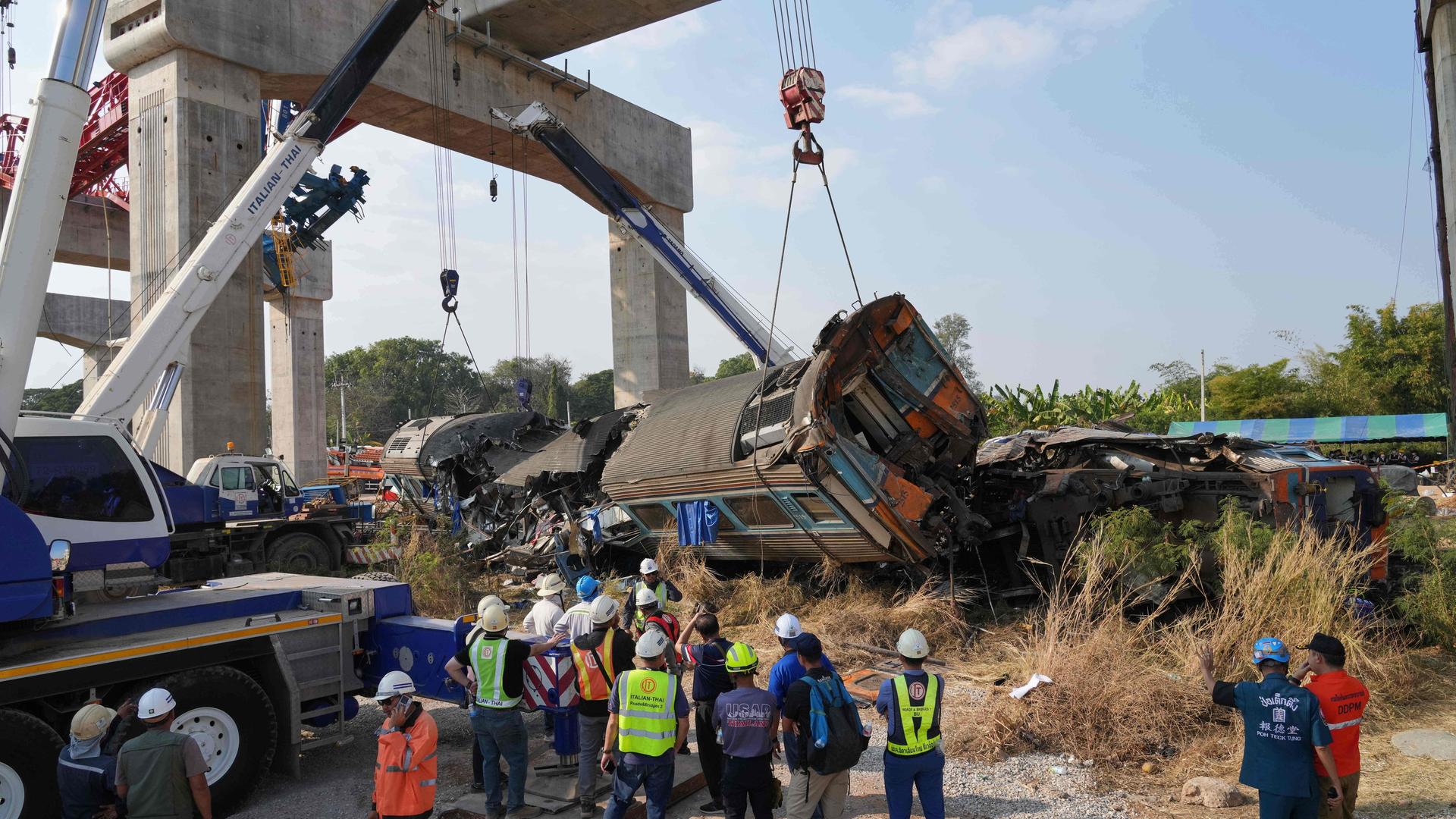 Hilfskräfte stehen nach einem Zugunglück an der Unfallstelle und versuchen, Zugteile mit Kränen anzuheben.