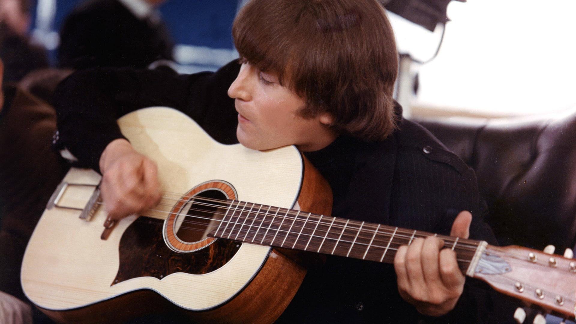 Der Musiker John Lennon. Er spielt eine Gitarre. 