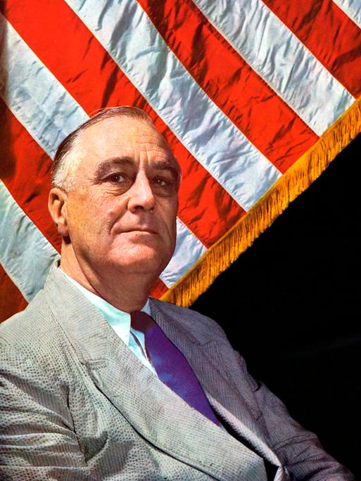 Farbiges Porträt von Franklin D. Roosevelt, der vor einer amerikanischen Flagge sitzt. Farbiges Porträt von Franklin D. Roosevelt, der vor einer amerikanischen Flagge sitzt.
