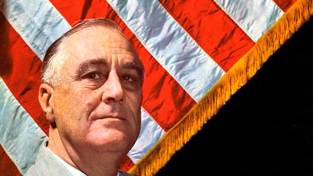 Farbiges Porträt von Franklin D. Roosevelt, der vor einer amerikanischen Flagge sitzt. Farbiges Porträt von Franklin D. Roosevelt, der vor einer amerikanischen Flagge sitzt.