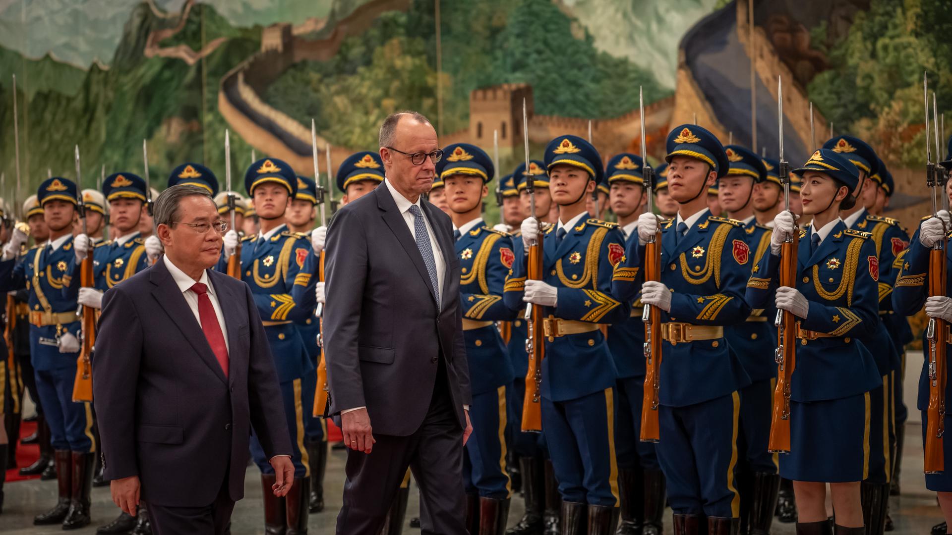 Das Foto zeigt Bundeskanzler Friedrich Merz und Chinas Ministerpräsidenten Li Qiang. Sie schreiten in der Großen Halle des Volkes in Peking eine Ehrengarde ab. Das Foto zeigt Bundeskanzler Friedrich Merz und Chinas Ministerpräsidenten Li Qiang. Sie schreiten in der Großen Halle des Volkes in Peking eine Ehrengarde ab.