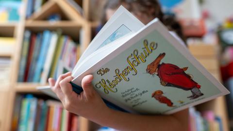 Ein Mädchen hält eine Ausgabe des Kinderbuchs „Die Häschenschule“ (Thienemann-Esslinger Verlag) in ihren Händen.