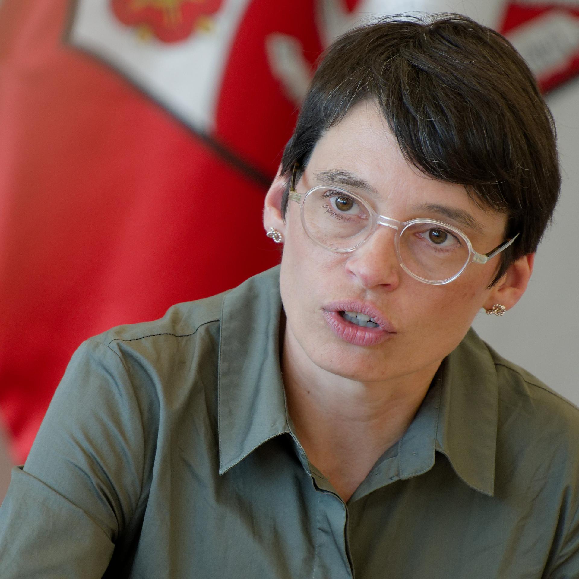 Josefine Paul, Ministerin für Kinder, Jugend, Familie, Gleichstellung, Flucht und Integration (Grüne) in Nordrhein-Westfalen, spricht bei einem Pressegespräch. Im Hintergrund ist die Flagge von NRW.