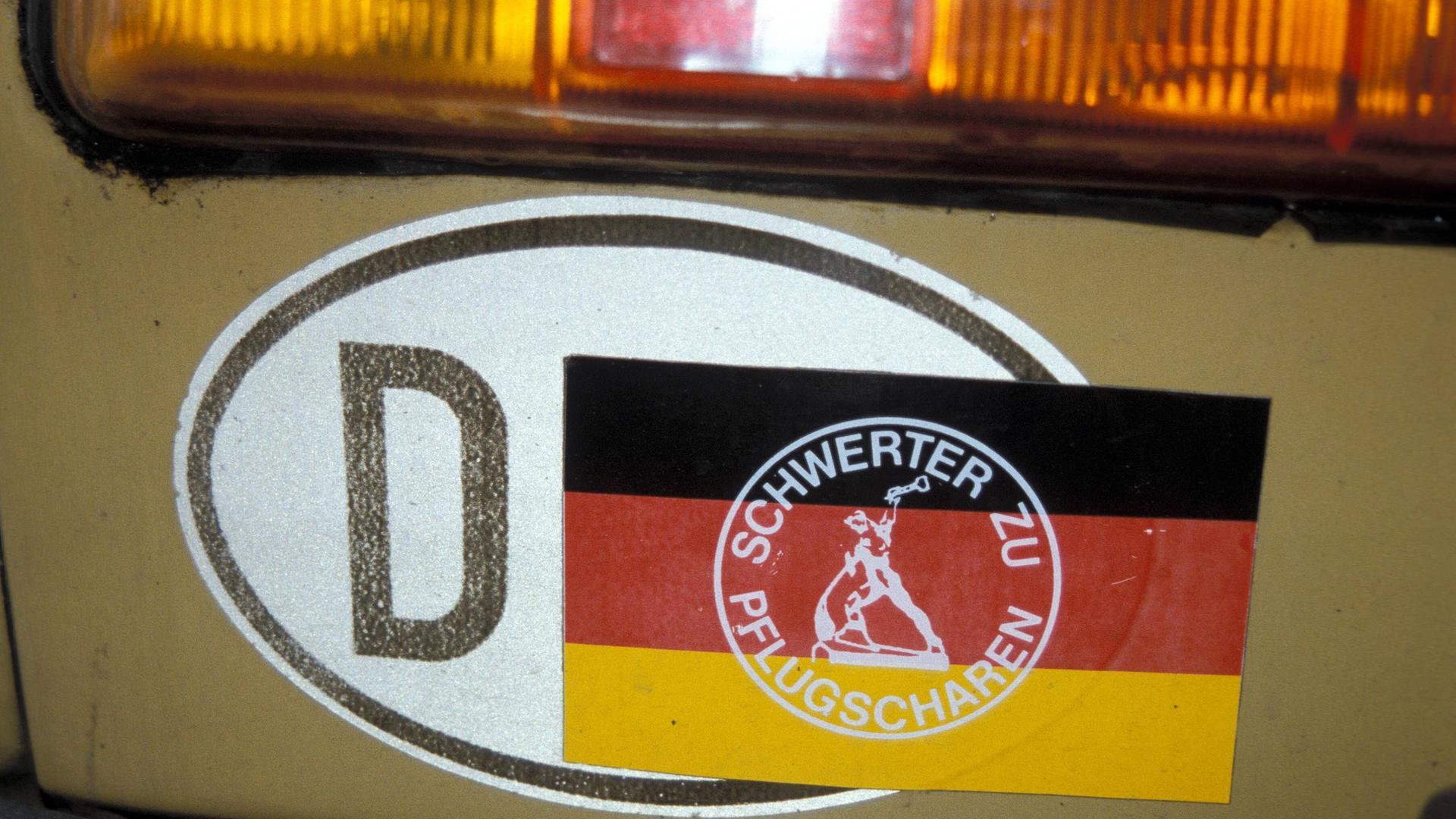 Ein DDR-Kennzeichen wurde mit einem Sticker mit der Aufschrift "Schwerter zu Pflugscharen" überklebt, sodass nur noch D für Deutschland zu lesen ist.