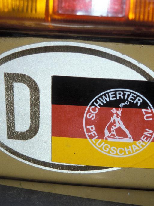 Ein DDR-Kennzeichen wurde mit einem Sticker mit der Aufschrift "Schwerter zu Pflugscharen" überklebt, sodass nur noch D für Deutschland zu lesen ist.