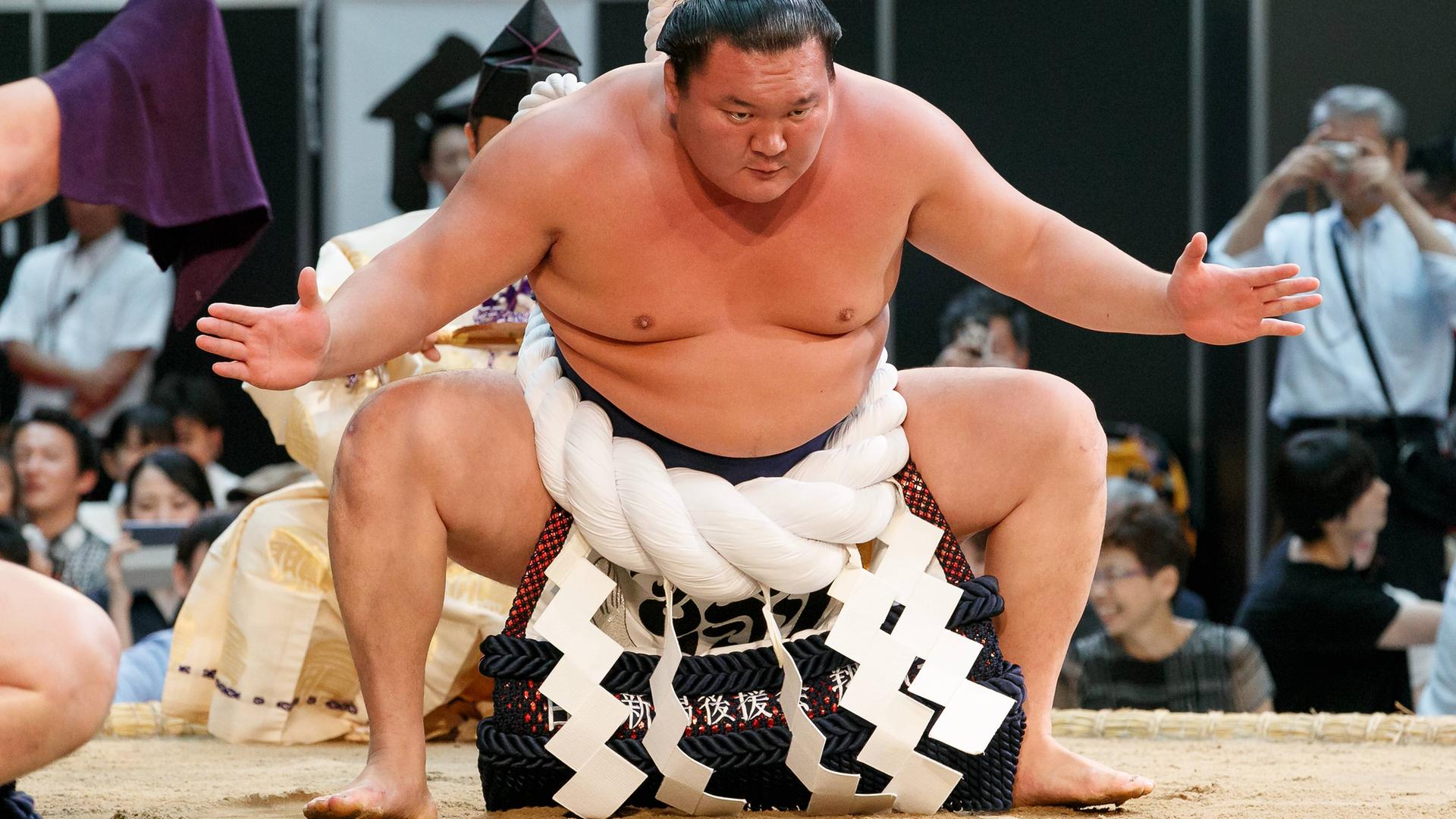 Hakuho Sho steht in Startposition in einem Ring in Tokio. Er trägt einen zeremoniellen Ringergürtel, einen Kesho-Mawashi. Hakuho Sho steht in Startposition in einem Ring in Tokio. Er trägt einen zeremoniellen Ringergürtel, einen Kesho-Mawashi.