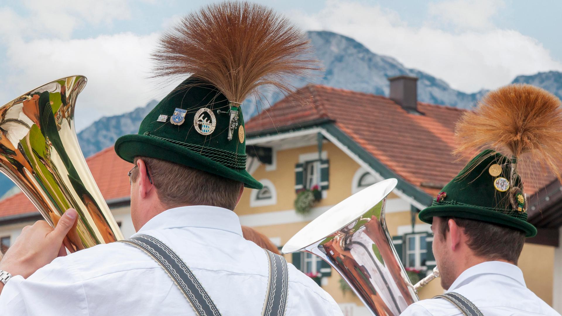 Zwei Blasmusiker in bayerischer Tracht vor Alpenkulisse
